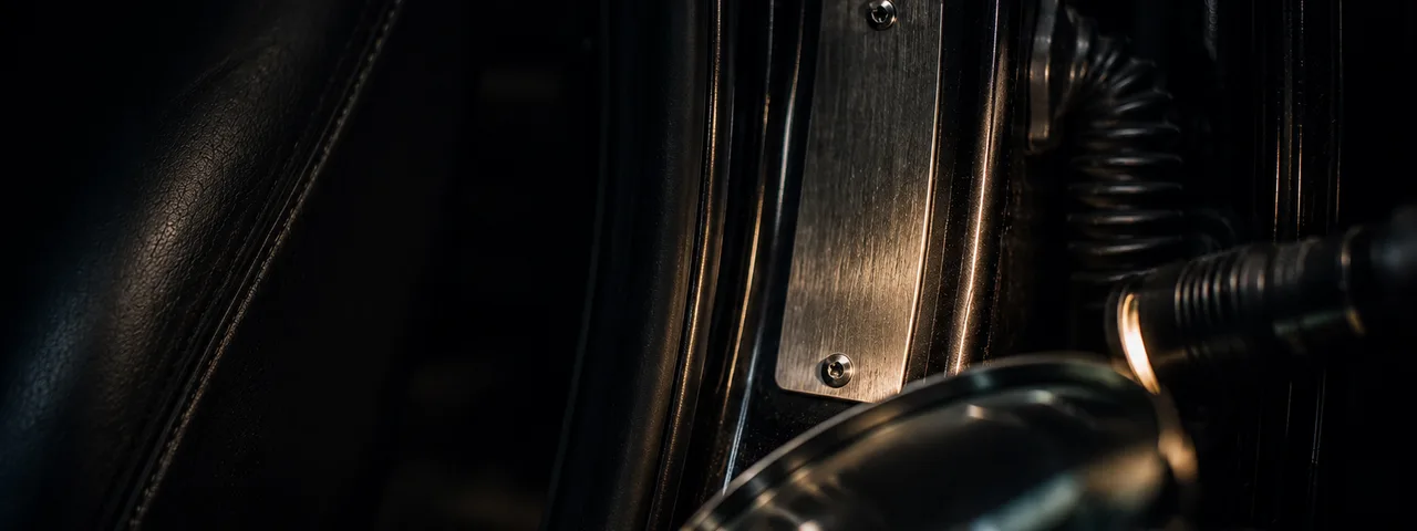 Dark vehicle door-jamb inspection close-up with a blank brushed metal plate and flashlight