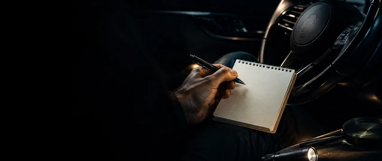 Driver seat forensic inspection scene with a blank notebook, pen, flashlight, and dark dashboard